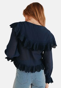 Marineblaue Bluse mit gerafften Akzenten am Ausschnitt und den Ärmeln, aus leichtem Stoff und mit lockerer Passform.