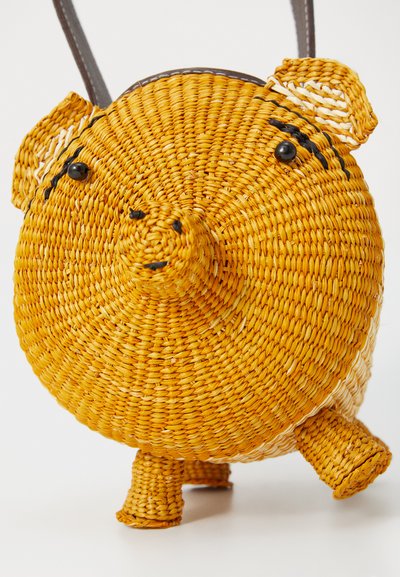 Round, yellow woven straw bag with a pig design, black bead eyes, small ears, and short legs. Features a brown strap for carrying.