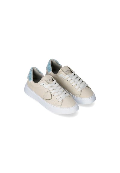 Sneakers in pelle beige con suole in gomma bianca, dotati di dettagli in blu testurizzato sul tallone e lacci bianchi. Finitura liscia, design low-top.