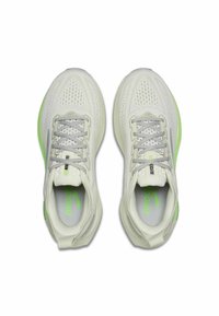 Een paar witte hardloopschoenen met grijze veters en groene accenten, gezien van boven, met een geventileerde mesh bovenkant en bedrukte binnenzolen.