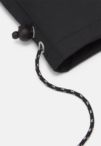 Pochette en tissu noir à texture lisse, équipée d'un œillet argenté et d'un cordon noir avec des accents blancs pour une fermeture sécurisée.