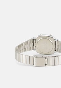 Montre en acier inoxydable argenté avec un boîtier rectangulaire, un bracelet à maillons et une boucle avec le nom de la marque "CASIO" gravé dessus.