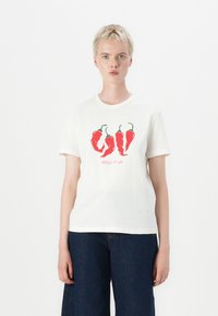 White cotton t-shirt featuring a graphic of red chili peppers and the text "SPICE IT UP" in pink. Short sleeves and a round neckline.