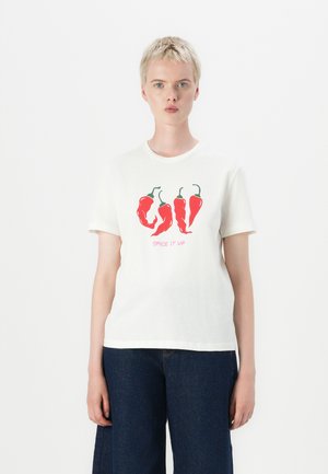 T-shirt in cotone bianco con grafica di peperoncini rossi e testo "SPICE IT UP" in rosa. Maniche corte e scollo rotondo.