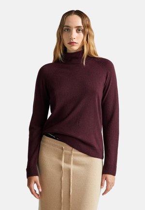 Suéter burdeos de cuello alto con mangas largas, hecho de una suave tela de punto. Combinado con una falda beige que presenta detalles de cordón.