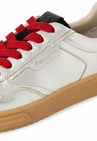 Sneaker in pelle argentata con lacci rossi, suola in gomma beige e accentuazione nera sul tallone. Presenta un design cucito e un logo stampato sul lato.
