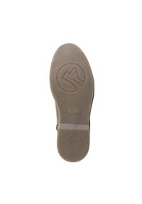 Suela de zapatilla en goma marrón claro, con estrías texturizadas y un logo con un símbolo de montaña. Plana, diseñada para la comodidad y el agarre.