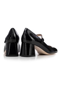 Scarpe col tacco in pelle patinata nera con punta quadrata, cinturino regolabile e tacco quadrato. Finitura testurizzata con un aspetto lucido, design minimalista.