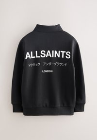 Fekete pulóver gallérral, nagy fehér felirattal "ALLSAINTS" és kisebb japán szöveggel, valamint "LONDON" felirattal a hátsó részén. Sima textúra.
