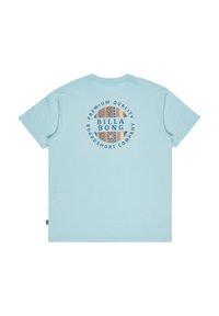 T-shirt in cotone azzurro chiaro con grafica circolare contenente il testo "BILLA BONG" e dettagli decorativi, maniche corte e colletto a girocollo.