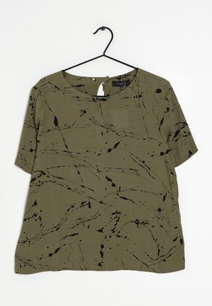 Olivgrünes kurzärmeliges Oberteil mit lockerem Schnitt, versehen mit schwarzen abstrakten Spritz- und Linienmustern. Abgerundeter Ausschnitt und weicher Stoff.