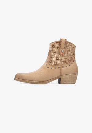 Stivale alla caviglia in camoscio color cuoio con design traforato e borchie decorative. Tacco basso a blocco; punta arrotondata e cuciture a contrasto lungo la suola.