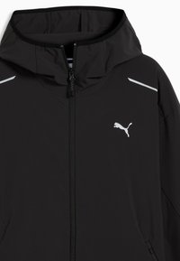 Μαύρο μπουφάν Puma με κουκούλα, φερμουάρ εμπρός, ανακλαστικές λεπτομέρειες στους ώμους και το λογότυπο Puma στο αριστερό στήθος.