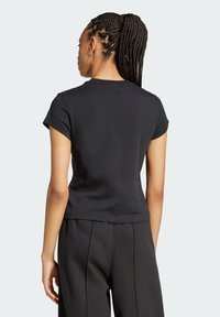 Tricou negru din bumbac cu mâneci scurte, design ajustat și o textură moale. Prezentând un stil minimalistic, cu un guler rotund și fără detalii proeminente.