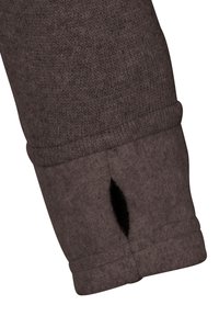 Brun stickad tröja med manschett som har en liten öppning och en texturerad yta. Tyget är mjukt med en lätt stretch och en vikt nederkant.