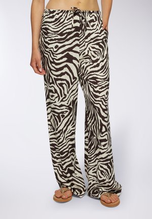Pantaloni a gamba larga in un tessuto beige con un motivo a strisce zebra nere. Presentano una vita elastica con cordino e tasche laterali.