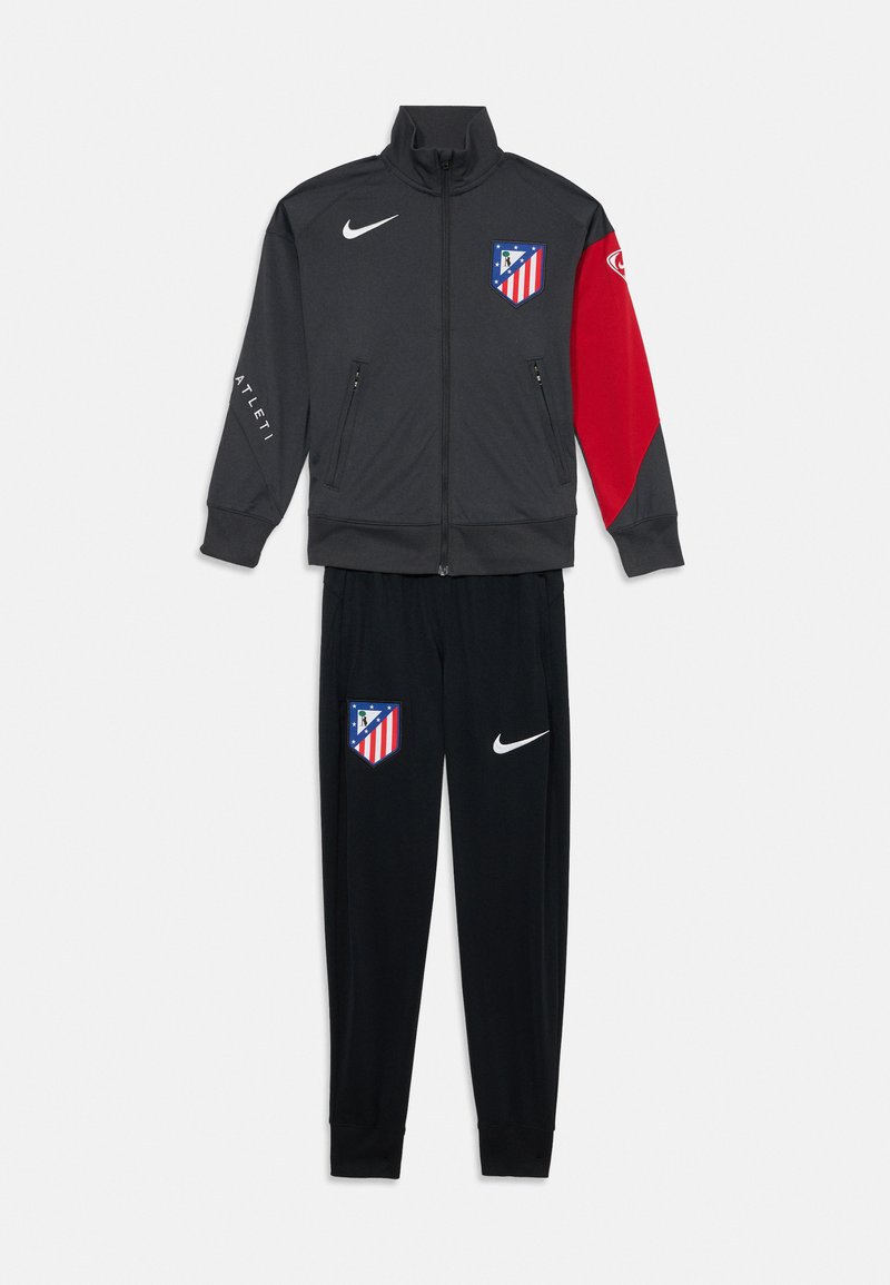 Nike Trainingsanzug in Dunkelgrau und Rot, bestehend aus einer Jacke mit Reißverschluss und Logo sowie passenden schwarzen Hosen mit Logo an der Seite. Hergestellt aus glattem Material.