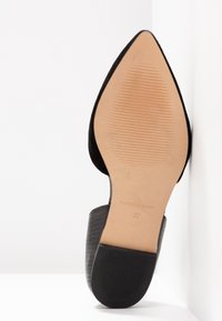 Chaussure à talon haut noire avec un bout pointu et une tige texturée. La semelle en cuir présente des stries, marquée "FABRIQUÉ EN ESPAGNE" et taille 37.