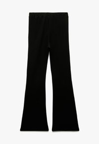 Sorte flared leggings lavet af blødt stof, med en elastisk talje og en glat tekstur, der har en tætsiddende form hele vejen igennem.