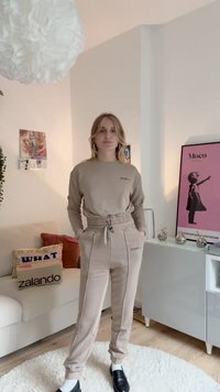 Μπεζ φούτερ και ταιριαστά φόρμα με ελαστική μέση. Οι παντελόνες διαθέτουν πλαϊνές τσέπες και υποκριτικές ραφές. Μαύρα παπούτσια.