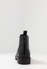 Botas de tobillo de cuero negro con un acabado suave, paneles laterales elásticos y una suela de goma gruesa y con dibujo. Tirador trasero para facilitar el calzado.