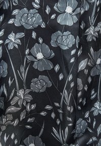 Tessuto scuro con motivo floreale in sfumature di grigio, con forme dettagliate di fiori e foglie, che creano un aspetto strutturato.