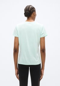 Ανοιχτό πράσινο κοντομάνικο μπλουζάκι από μαλακό, ελαφρύ ύφασμα με στρογγυλή λαιμόκοψη και άνετη εφαρμογή, με μινιμαλιστικό σχεδιασμό.