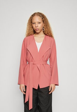 Pink lightweight jacket with a shawl collar, tie waist, and long sleeves, paired with a white top and black pants.