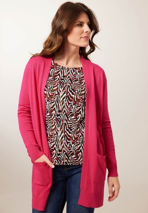 Fuchsia lange cardigan met open voorkant en zakken, gelaagd over een multicolore dierenprint top. Soepele textuur, casual ontwerp.