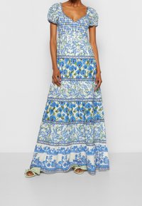 Květinové maxi šaty s nabíranými rukávy, mačkanou oblastí a modrozelenými vzory. Sukně po kolena s bílými akcenty a mekkou texturou.