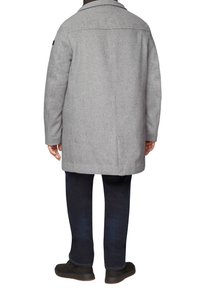 Grijze wolmix jas met een rechte snit, notch revers en een enkele achterkantopening. Gepaard met donkere jeans en zwarte schoenen.