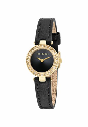 Zwarte leren horloge met gouden bezel, zwarte wijzerplaat en kristalaccenten. Beschikt over een gestructureerde achterkant en het merk 'Ted Baker'.
