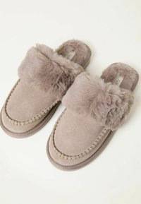 Light brown suede slippers with thick, fluffy fur lining and trim, stitched details, and open-back design on a white background.