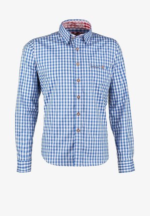 Homme portant un lederhosen marron traditionnel avec des bretelles, une chemise à carreaux bleue, des chaussettes montantes et des chaussures marron, marchant en avant.