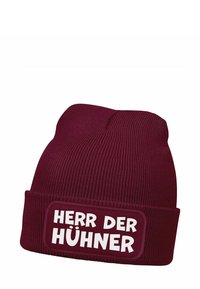 Burgundy knit beanie featuring a white patch with the text "HERR DER HÜHNER." The fabric is ribbed and stretchy for comfort.