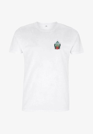 T-shirt en coton blanc avec un petit personnage vert illustré avec une fleur et des détails géométriques sur le côté gauche de la poitrine.