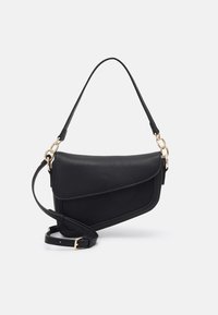 Borsa a spalla in pelle nera testurizzata con patta asimmetrica, catene in tono oro e tracolla regolabile su sfondo bianco.