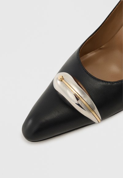 Zwarte leren puntige schoen met een metallic zilveren en gouden accent over de bovenzijde, met een gladde textuur en een slank ontwerp.