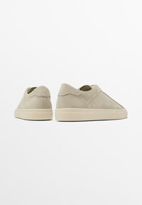 Béžové semišové boty na slip-on s kulatou špičkou a šitými detaily, s plochou gumovou podrážkou a minimalistickým designem.