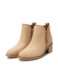 Botas de tobillo tejidas en color beige con puntera redonda y cremalleras laterales. Patrón texturizado con un tacón bajo y un forro interior suave.