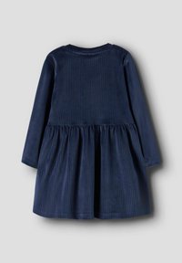 Granatowa sukienka z sztruksu z długimi rękawami, teksturą prążkowaną, okrągłym dekoltem i rozkloszowanym dołem. Ukazana z tyłu.
