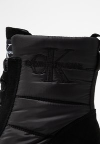 Černé boty s hladkým nylonovým svrškem, prošívanými částmi, suede akcentem a embosovaným logem Calvin Klein Jeans na boku.