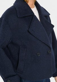Námořnicky modré dvouřadové sako z vlněné směsi s velkými zářezovými klopami, bočními kapsami a černými knoflíky, zdobené texturovaným povrchem.