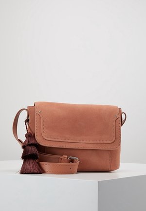 Bruine suède crossbodytas met klep en donkerbruine kwastdetail, tentoongesteld op een wit voetstuk tegen een effen achtergrond.