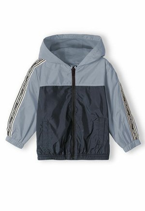 Chaqueta con capucha en azul marino y claro, con cremallera frontal, puños elásticos, bolsillos laterales y detalles de rayas en las mangas. Fabricada en material ligero.