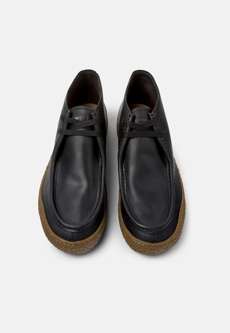 Black leather shoes with a rounded toe, laced design, and a textured brown rubber sole. Clean, minimalist style with no additional embellishments.