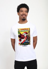 Camiseta blanca de algodón con un diseño gráfico de cómic de Capitán América, con colores vivos, personajes y texto que dice "¡UN MUNDO NUEVO Y VALIENTE!"