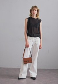 Top negru fără mâneci, pantaloni albi largi, geantă maro cu curea și pantofi negri. Texturi netede, design minimalist.