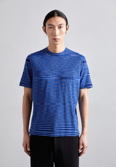 T-shirt bleu rayé en tissu léger, avec des lignes horizontales de différentes largeurs. Encolure ronde et manches courtes.