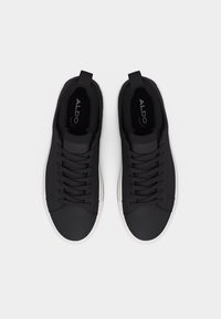 Baskets basses noires avec lacets noirs, semelles blanches et languettes de tirage, de marque Aldo, vues de dessus sur un fond clair.
